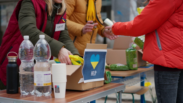 The volunteers distributing food and drink to refugees on the Ukrainian border, humanitarian aid concept.