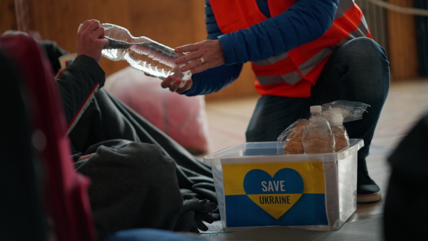 Ukrainian war refugees in a temporary shelter and help center getting drinks from volunteers.