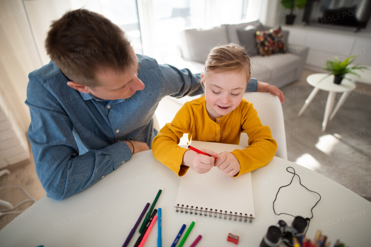 A father with his little daughter with Down syndrome learning at home.