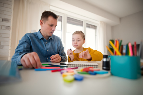 A father with his little daughter with Down syndrome learning at home.