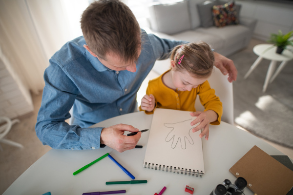 A father with his little daughter with Down syndrome learning at home.