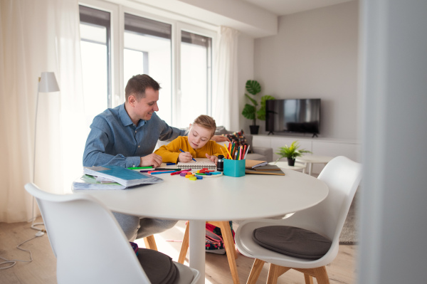 A father with his little daughter with Down syndrome learning at home.