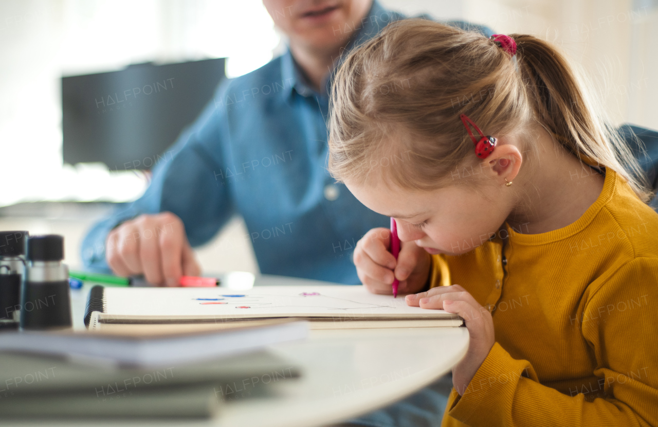 A father with his little daughter with Down syndrome learning at home.