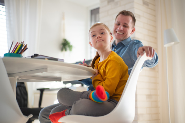 A father with his little daughter with Down syndrome learning at home.