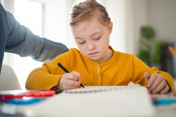 A father with his little daughter with Down syndrome learning at home.