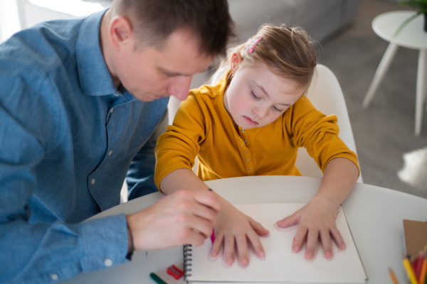 A father with his little daughter with Down syndrome learning at home.