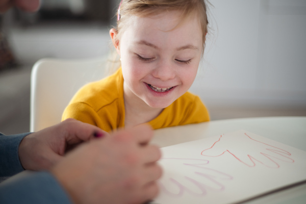 A father with his little daughter with Down syndrome drawing at home.