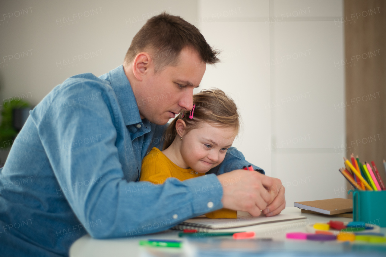 A father with his little daughter with Down syndrome learning at home.