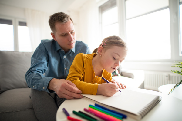 A father with his little daughter with Down syndrome learning at home.