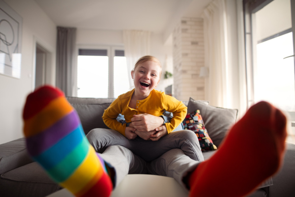 A cheerful little girl with Down syndrome having fun with her father at home.