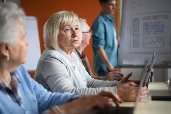 A senior group in retirement home with young instructor learning together in computer class