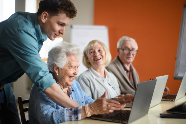 A senior group in retirement home with young instructor learning together in computer class