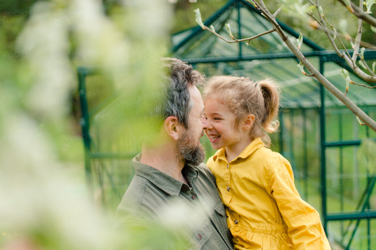 A father with his little daughter bonding in front of eco greenhouse, sustainable lifestyle.