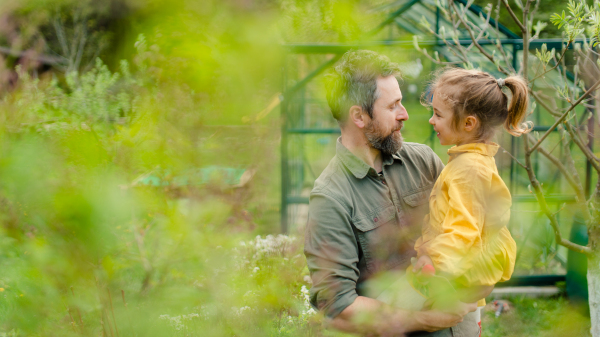 A gather with his little daughter bonding in front of eco greenhouse, sustainable lifestyle.