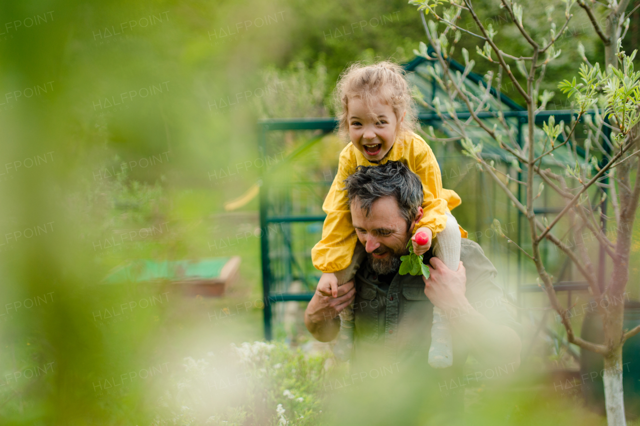 A father with his little daughter bonding in front of eco greenhouse, sustainable lifestyle.