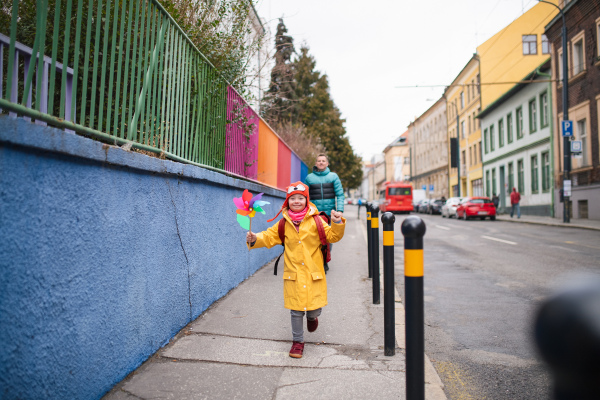 A father taking his little daughter with Down syndrome to school, outdoors in street.