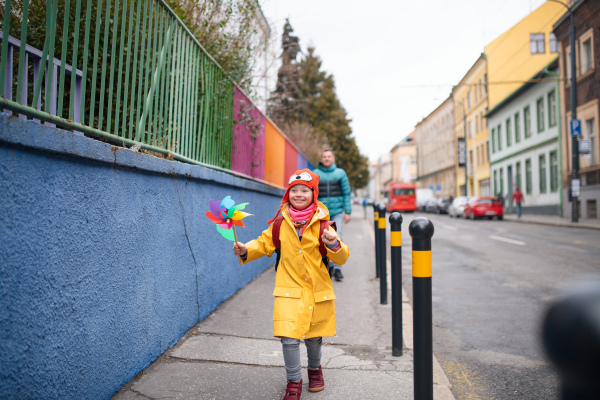 A father taking his little daughter with Down syndrome to school, outdoors in street.