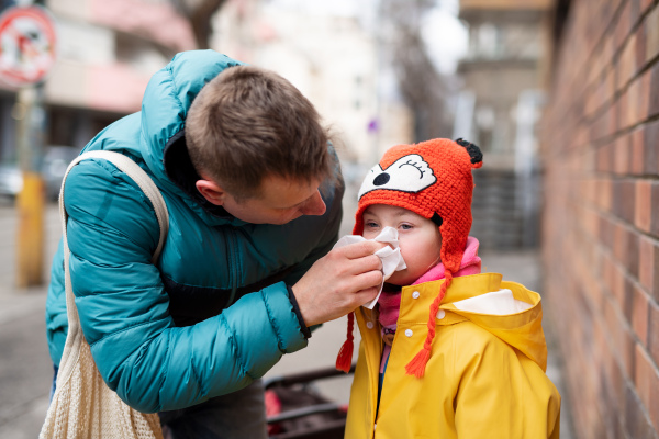 A father with his little daughter with Down syndrome on walk in town in winter.