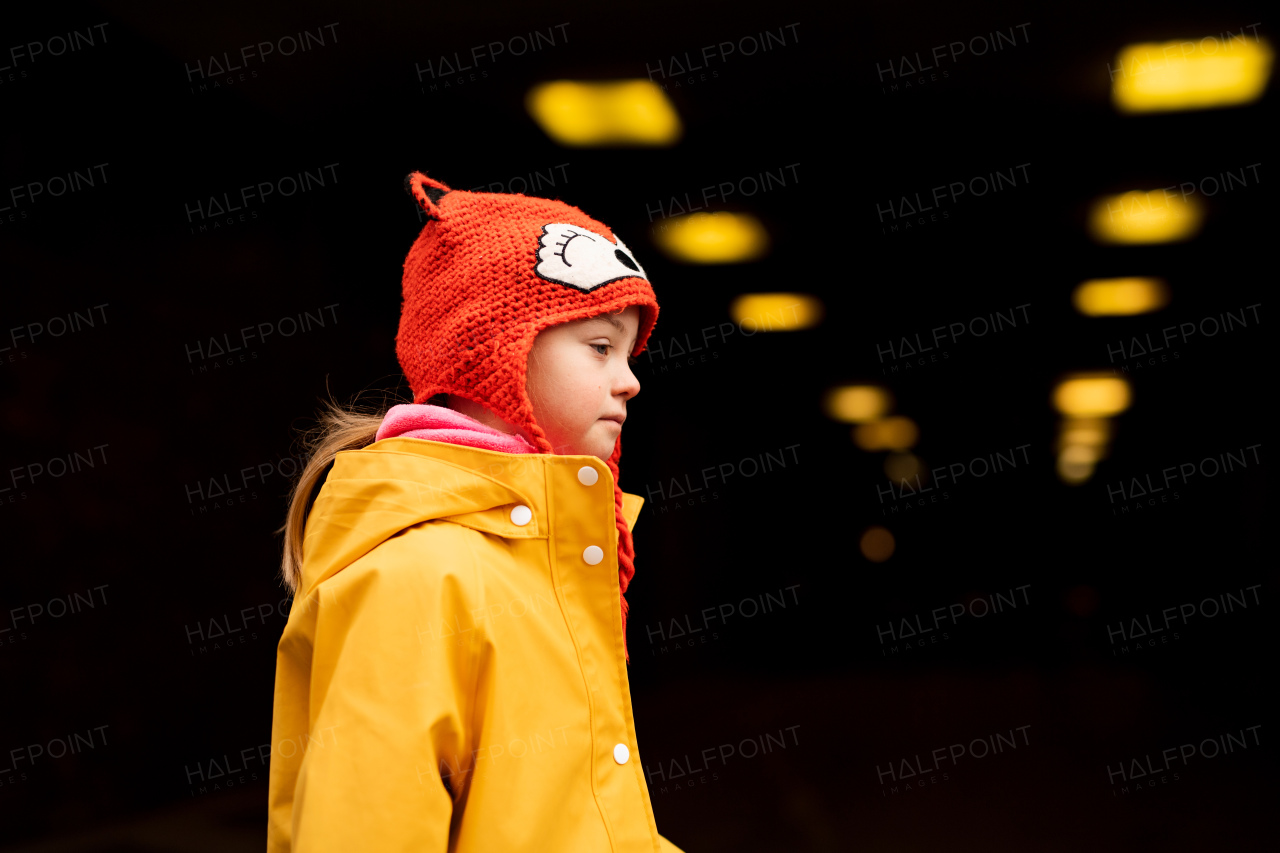 A little girl with Down syndrome outdoors at nigh in winter.