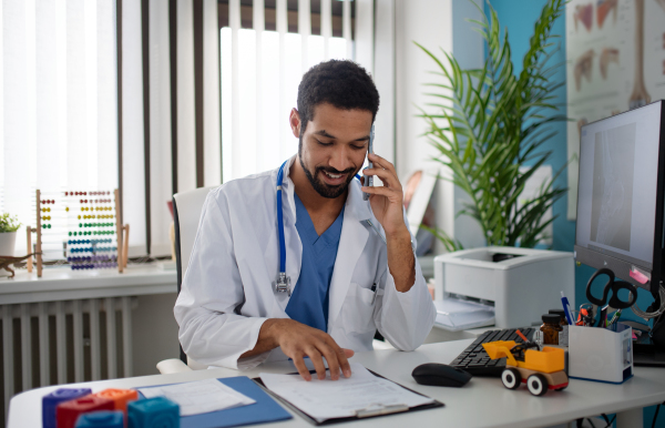 A young male doctor managing phone calls in his office.