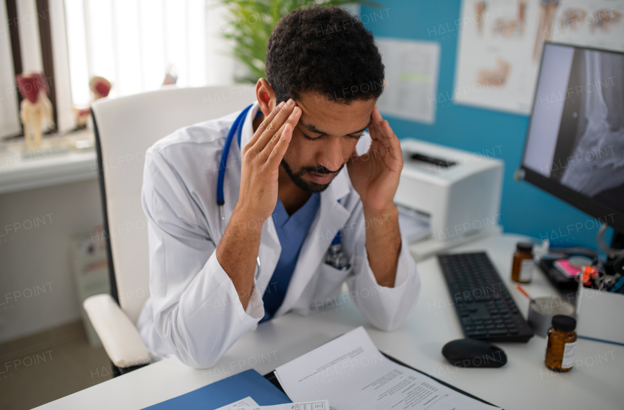 A depressed young male doctor with headache sitting in his office