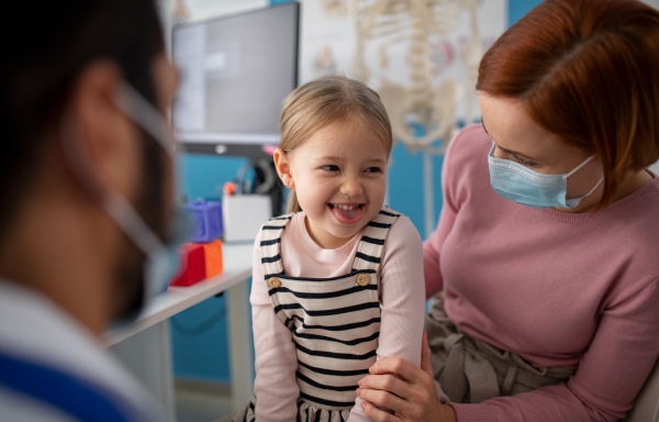 a Little girl with her mother at doctor's office on consultation, coronavirus concept.