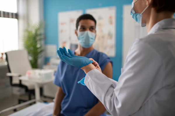 A close-up of doctor putting on gloves in her office.