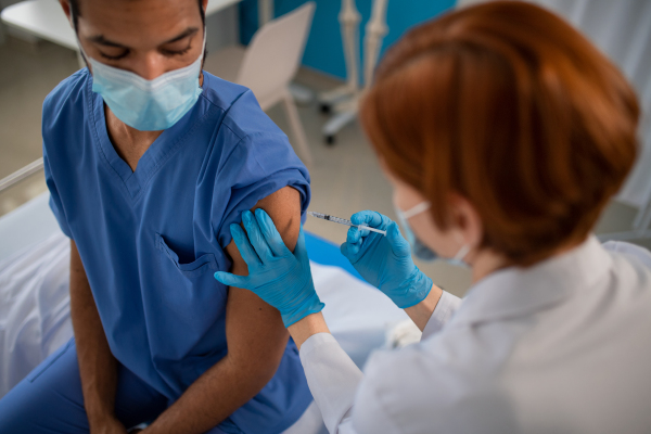 A high angle view of of doctor getting covid-19 vaccince from his colleague.