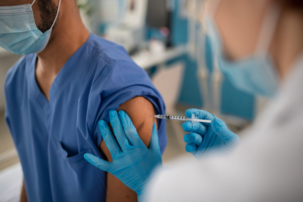 A close-up of doctor getting covid-19 vaccince from his colleague.