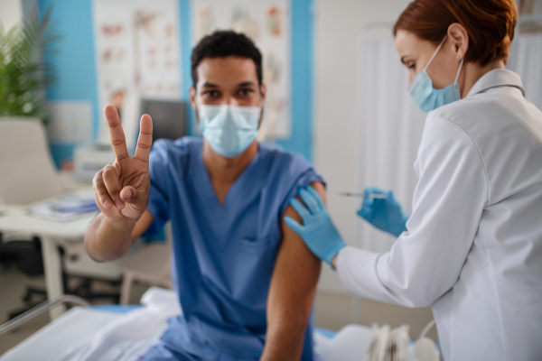 A doctor getting covid-19 vaccince from his colleague.