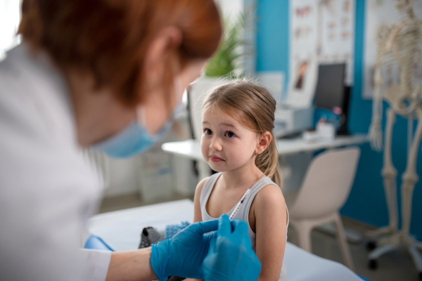 A worried little girl getting vaccinated in doctor's office.