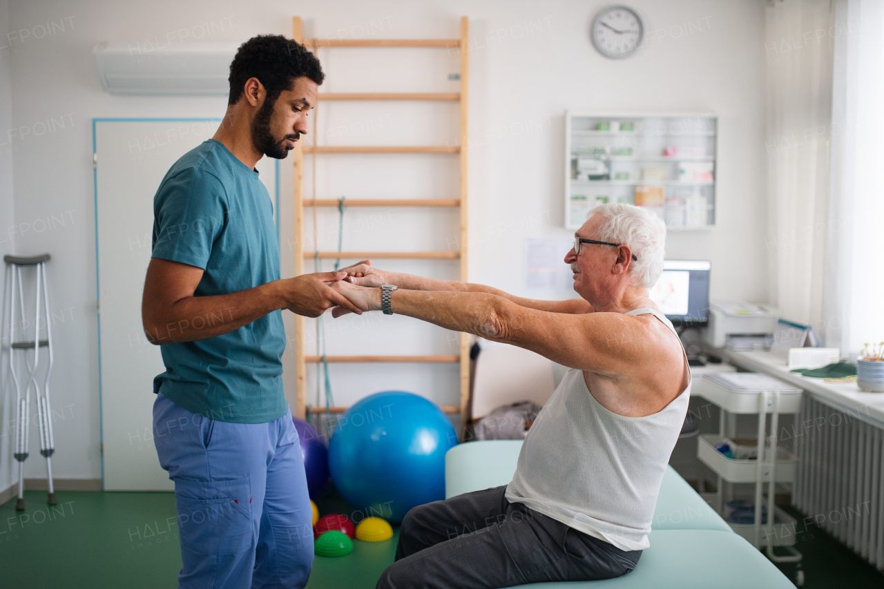 A young physiotherapist exercising with senior patient in a physic room