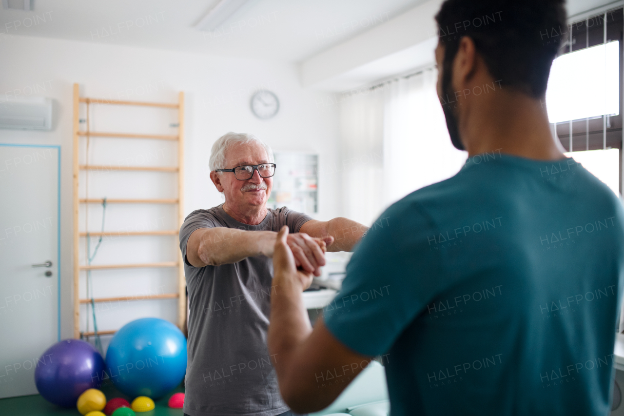 A young physiotherapist exercising with senior patient in a physic room