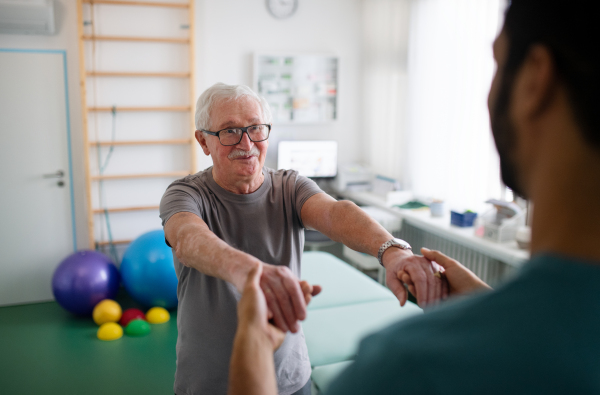 A young physiotherapist exercising with senior patient in a physic room