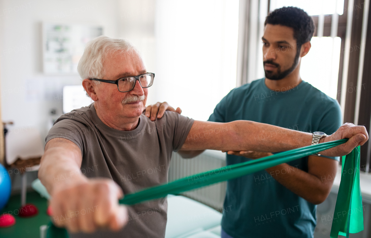 A young physiotherapist exercising with senior patient in a physic room