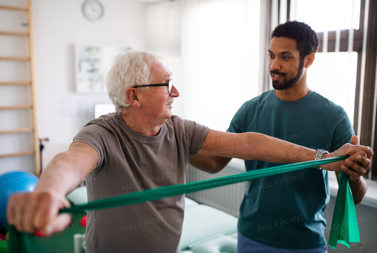 A young physiotherapist exercising with senior patient in a physic room