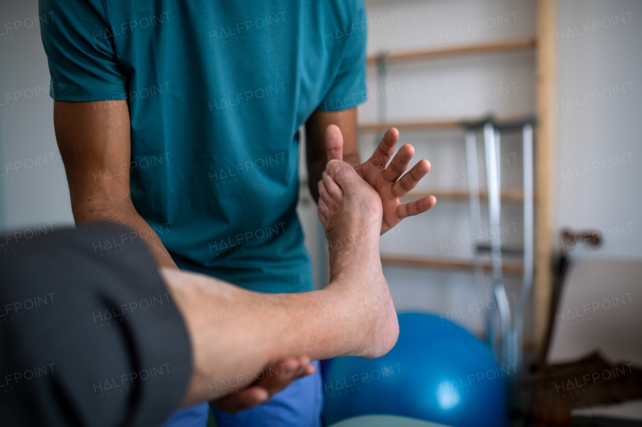 A close-up of physiotherapist exercising with senior patient's leg in a physic room.