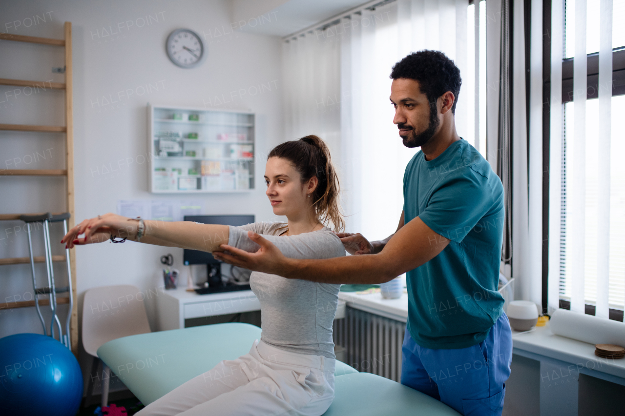 A young male physiotherapist examining young woman patient in a physic room