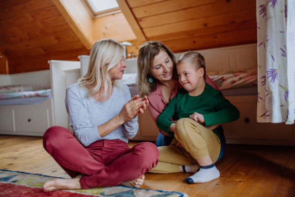 A boy with Down syndrome with his mother and grandmother at home.