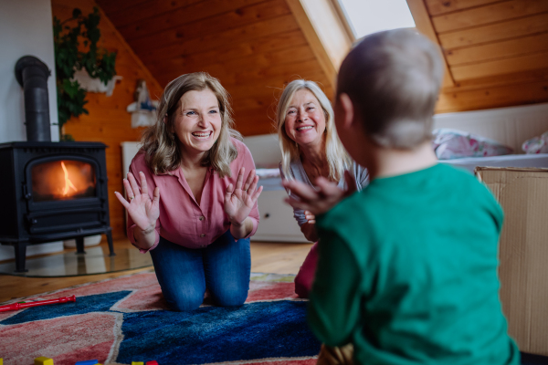 A boy with Down syndrome with his mother and grandmother playing together at home.