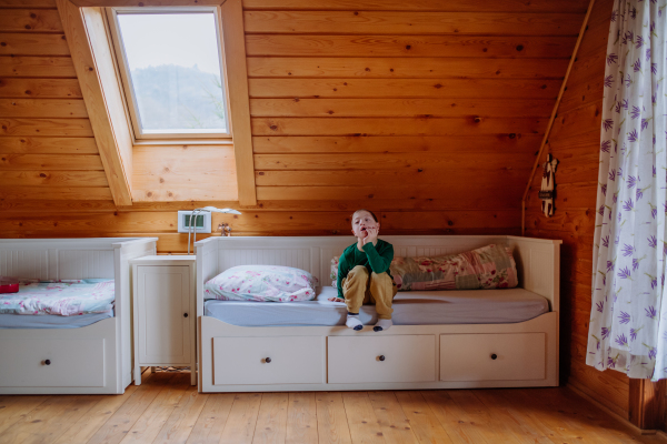 A little boy with Down syndrome sitting on bed at home.