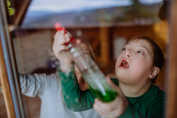 A boy with Down syndrome with his mother cleaning window at home.