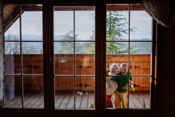 A boy with Down syndrome with his mother and grandmother cleaning window at home.