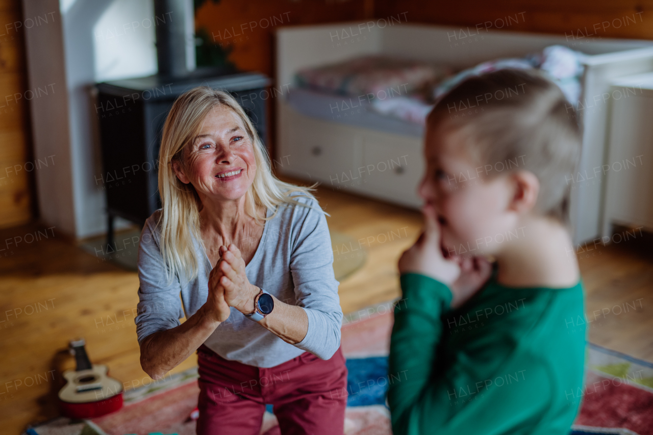 A happy boy with Down syndrome playing with his grandmother at home.