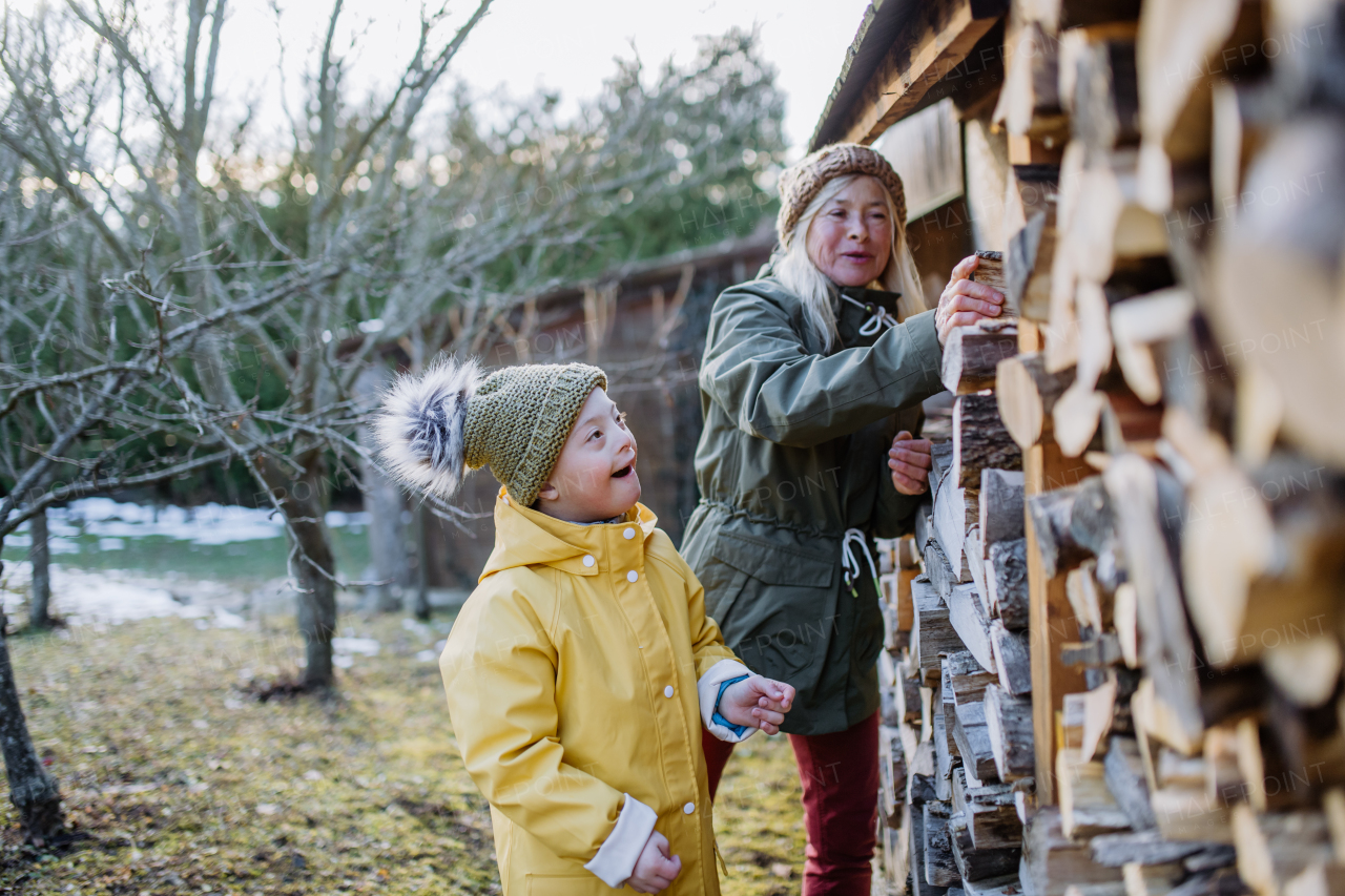 A boy with Down syndrome working in garden in winter with his grandmother.