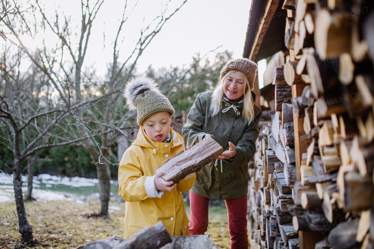 A boy with Down syndrome working in garden in winter with his grandmother.