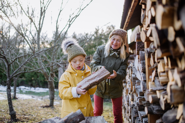 A boy with Down syndrome working in garden in winter with his grandmother.