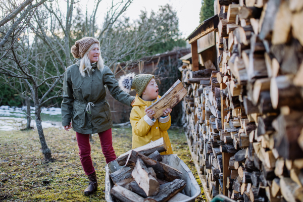 A boy with Down syndrome working in garden in winter with his grandmother.