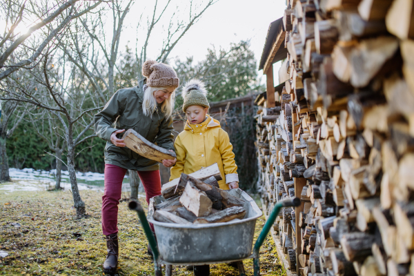 A boy with Down syndrome working in garden in winter with his grandmother.