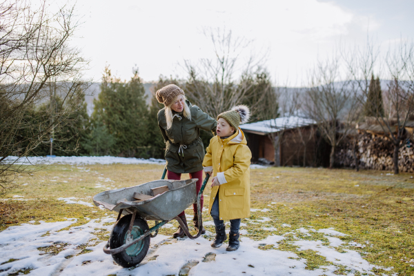 A boy with Down syndrome working in garden in winter with his grandmother.